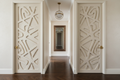 Luxury residential hallway with custom millwork door panels in off-white with brushed brass lever hardware