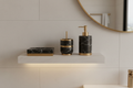 4-piece Nero Marquina marble bathroom accessory set on white oak shelf with brushed brass accents in warm vanity light