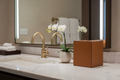 Cognac leatherette tissue box cover on luxury hotel bathroom vanity beside marble sink and orchid