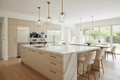 Luxury open-plan kitchen with bespoke quartzite top and lacquer base island, pendant lights and professional appliances